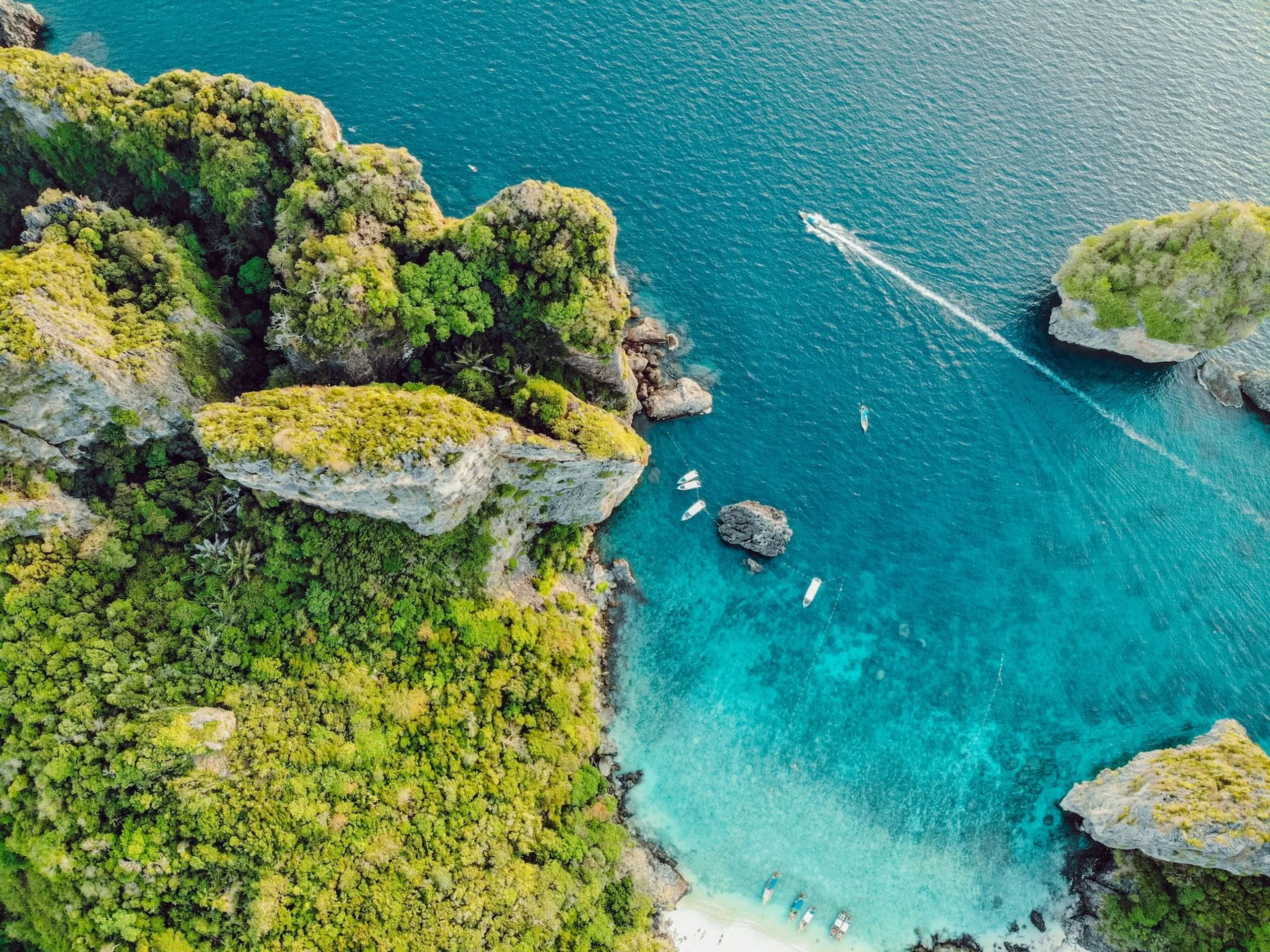 Aerial view of mountains and ocean with speed boat in Thailand