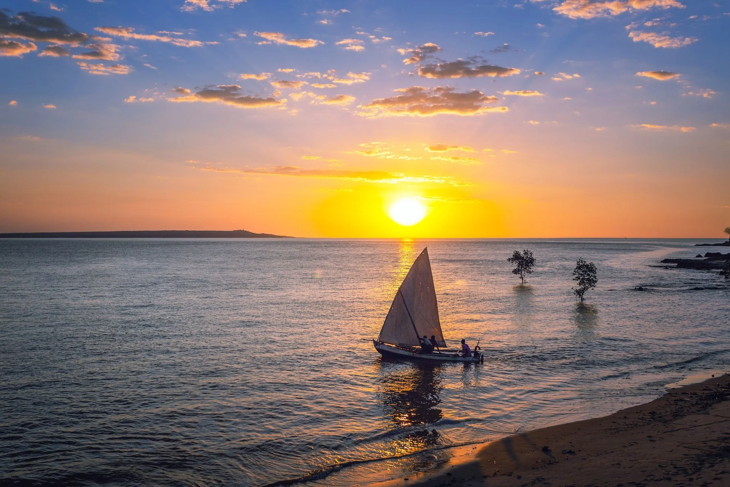 Dhow sailing across the ocean as the sun sets