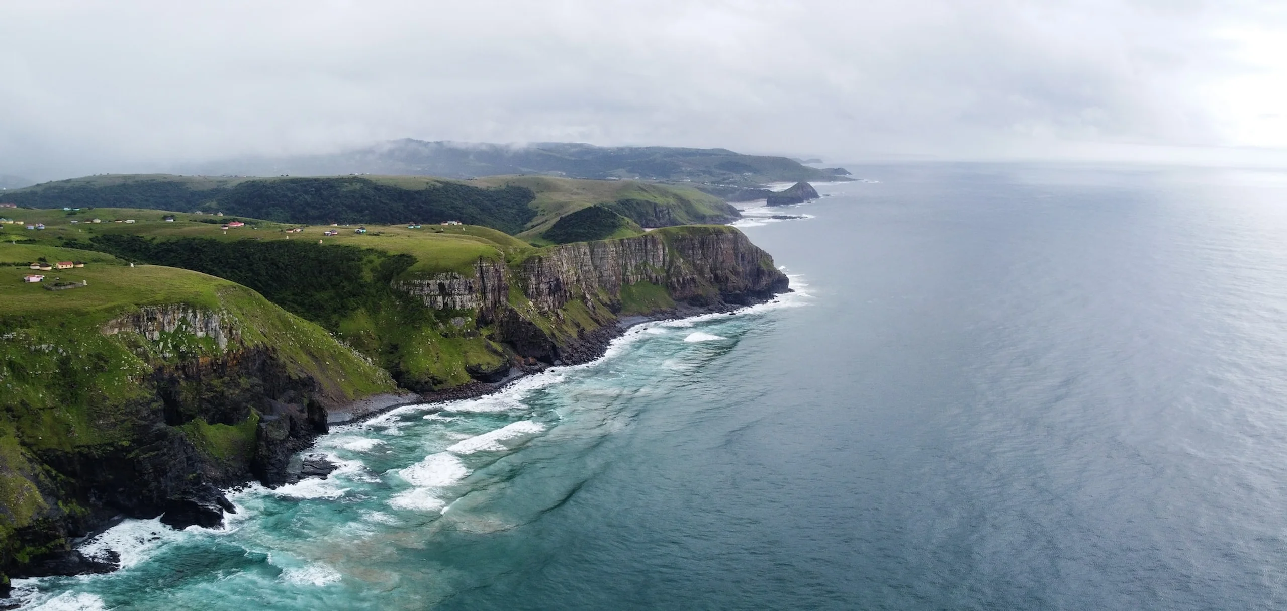 Green hills of Eastern Cape falling leading into the ocean on a cloudy day