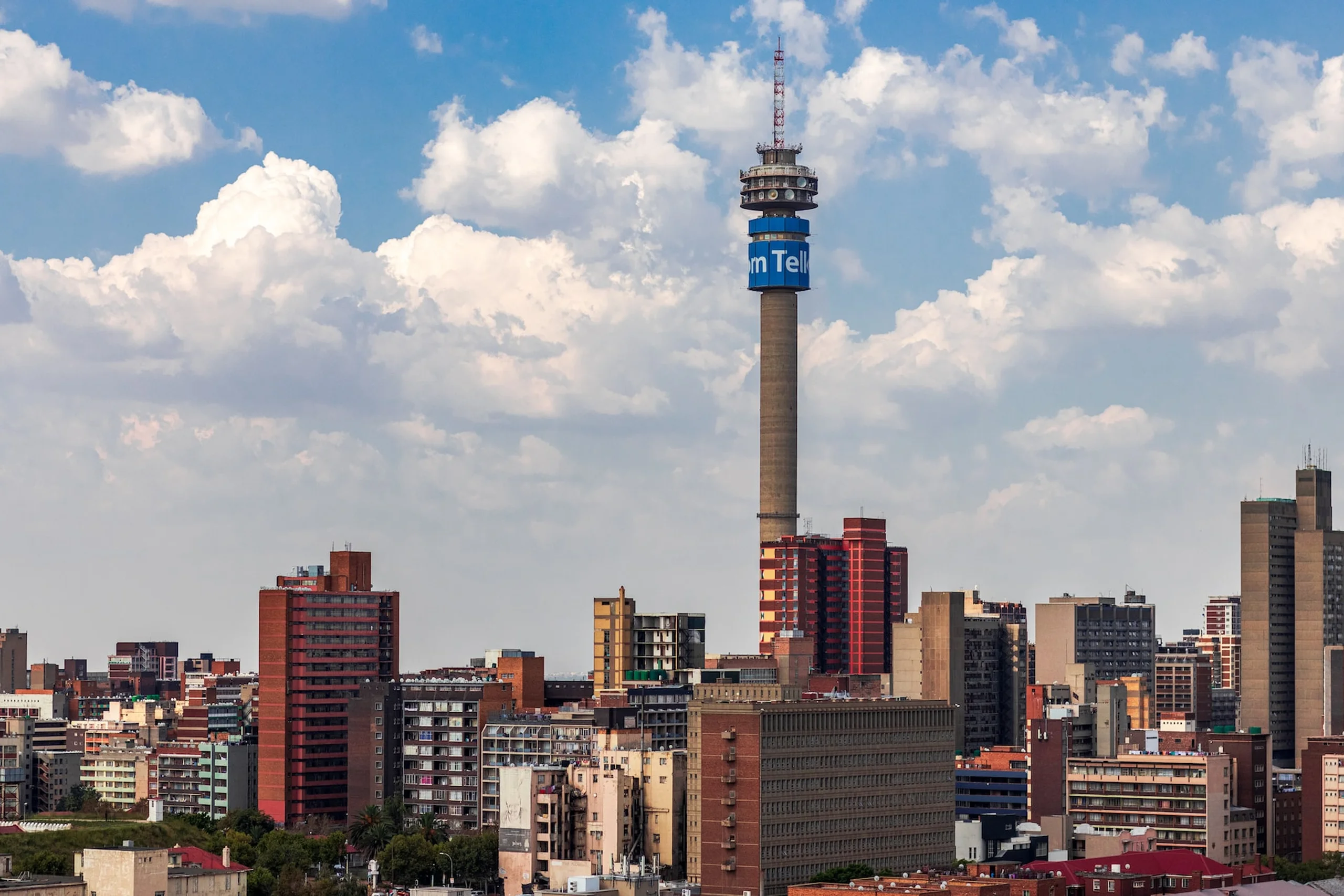 Hillbrow tower and Johannesburg city skyline of buildings with cloudy blue sky